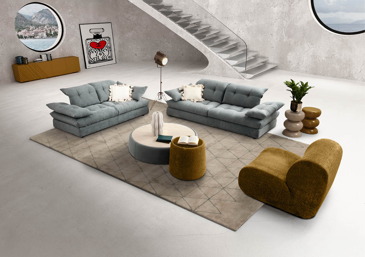 Salon moderne avec deux canap s gris, un fauteuil beige, une table basse ronde, un tapis et un escalier en b ton dans un espace minimaliste avec deux fen tres rondes. Description g n r e par IA